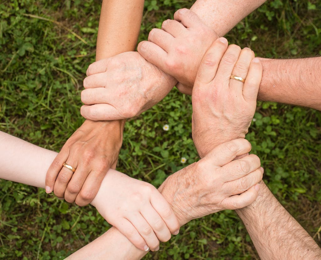 KollegialeZEIT Close-up of diverse hands forming a connection, symbolizing teamwork and unity outdoors.